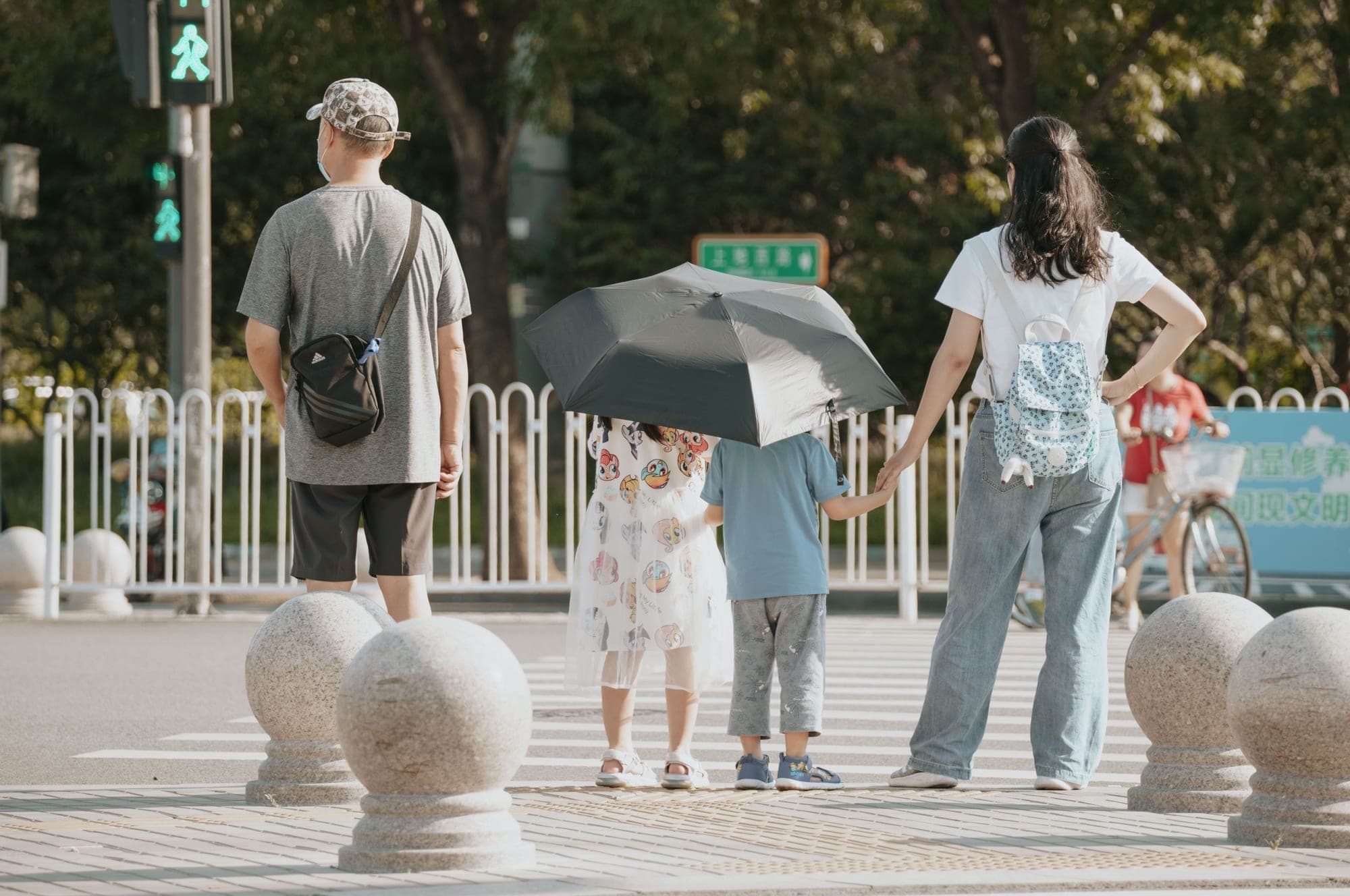 A family holding hands as they wait to cross a city street