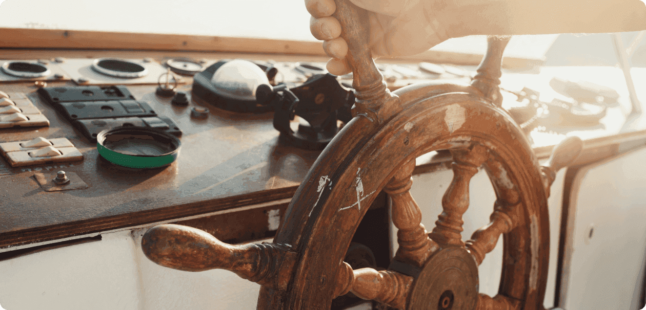 Hands steering a ship’s wheel