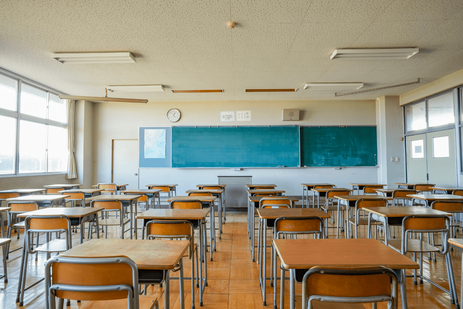 Empty classroom with rows of wooden desks facing a chalkboard